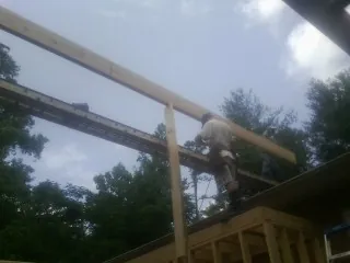 Carpenter setting a ridge beam over a new addition frame — Ice Dam Removal by Roofing Brothers in Carrollton