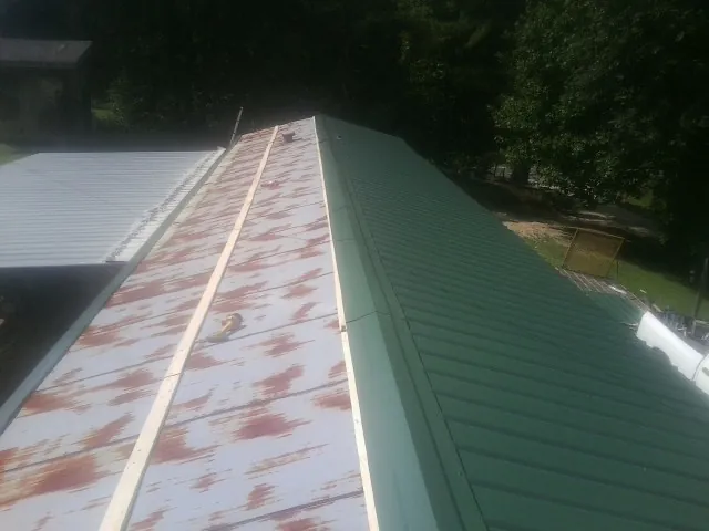 Old rusted panels beside newly installed green metal roofing — Wind Damage Roof Repair by Roofing Brothers in Carrollton