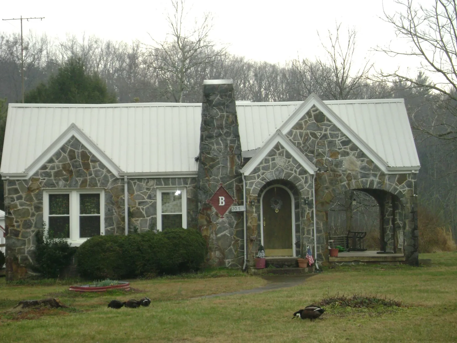 White metal roof on a stone cottage with steep gables in Carrollton